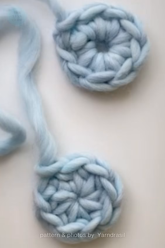 Two light blue crocheted pieces made from thick, chunky yarn shown on a white background, highlighting an open center loop on the top piece and a perfectly closed center loop below it. Curated by Ariana of TheYarnCrew.
